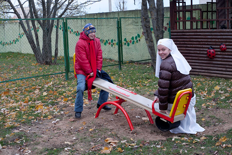 сестра милосердия с ребенком на качелях